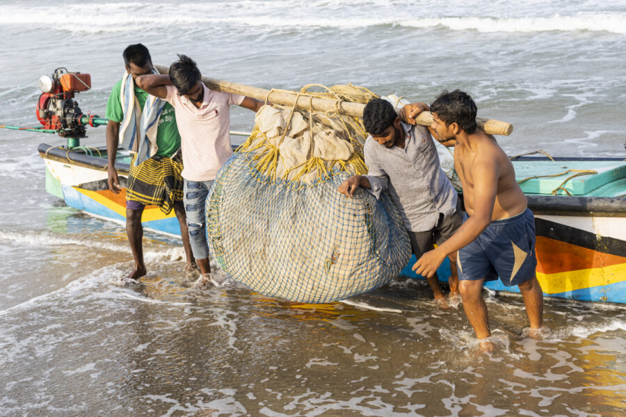 18 November 2022, Mangamaripeta, Andhra Pradesh, India- Fishermen unload nets from their boat on the beach. A cyclone warning and strong winds forced many fishermen to not venture into the sea and bring their boats ashore.This photo mission has been supported by Central Institute of Fisheries Technology (ICAR- CIFT), India.